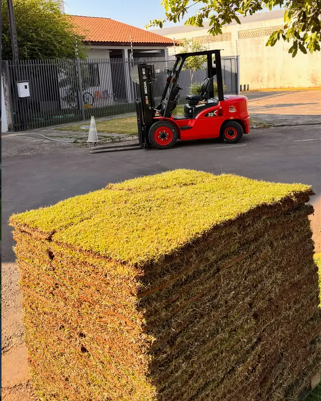 Palete de placas de grama empilhadas e a empilhadeira da Grameira Sinop numa rua de Sinop